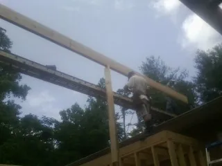 Carpenter setting a ridge beam over a new addition frame in Otter Rock