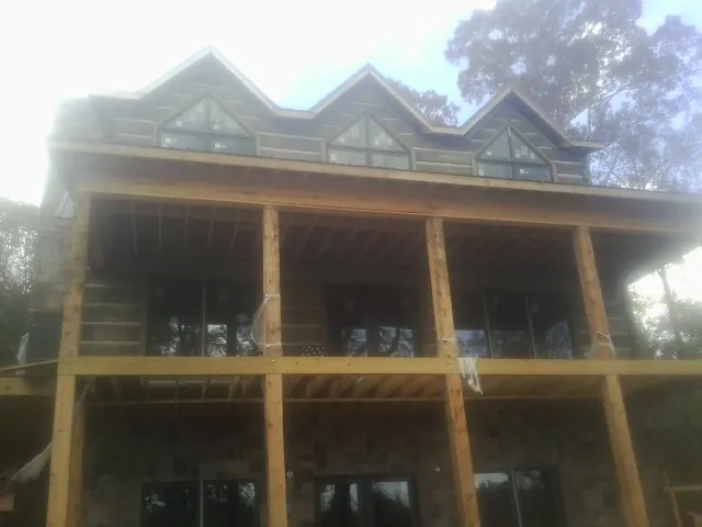 Dormers and porch framing on a large log home under construction — Roof Coating work by our crew in Otter Rock