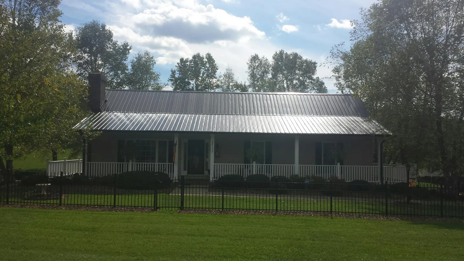 Gray metal roof on a brick ranch with a full width front porch — Gutter Guard Installation work by our crew in Otter Rock