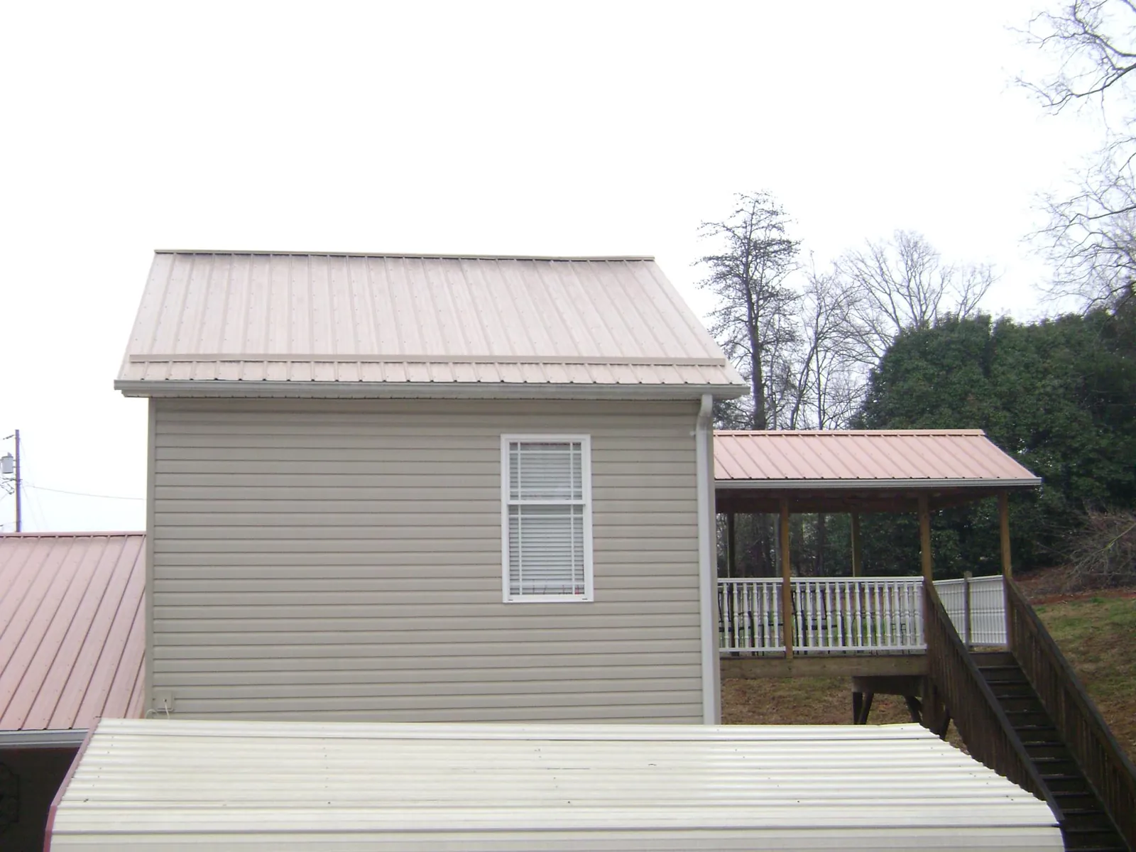 Tan metal roofs on a two story addition and attached porch, from a Roof Replacement job in Otter Rock