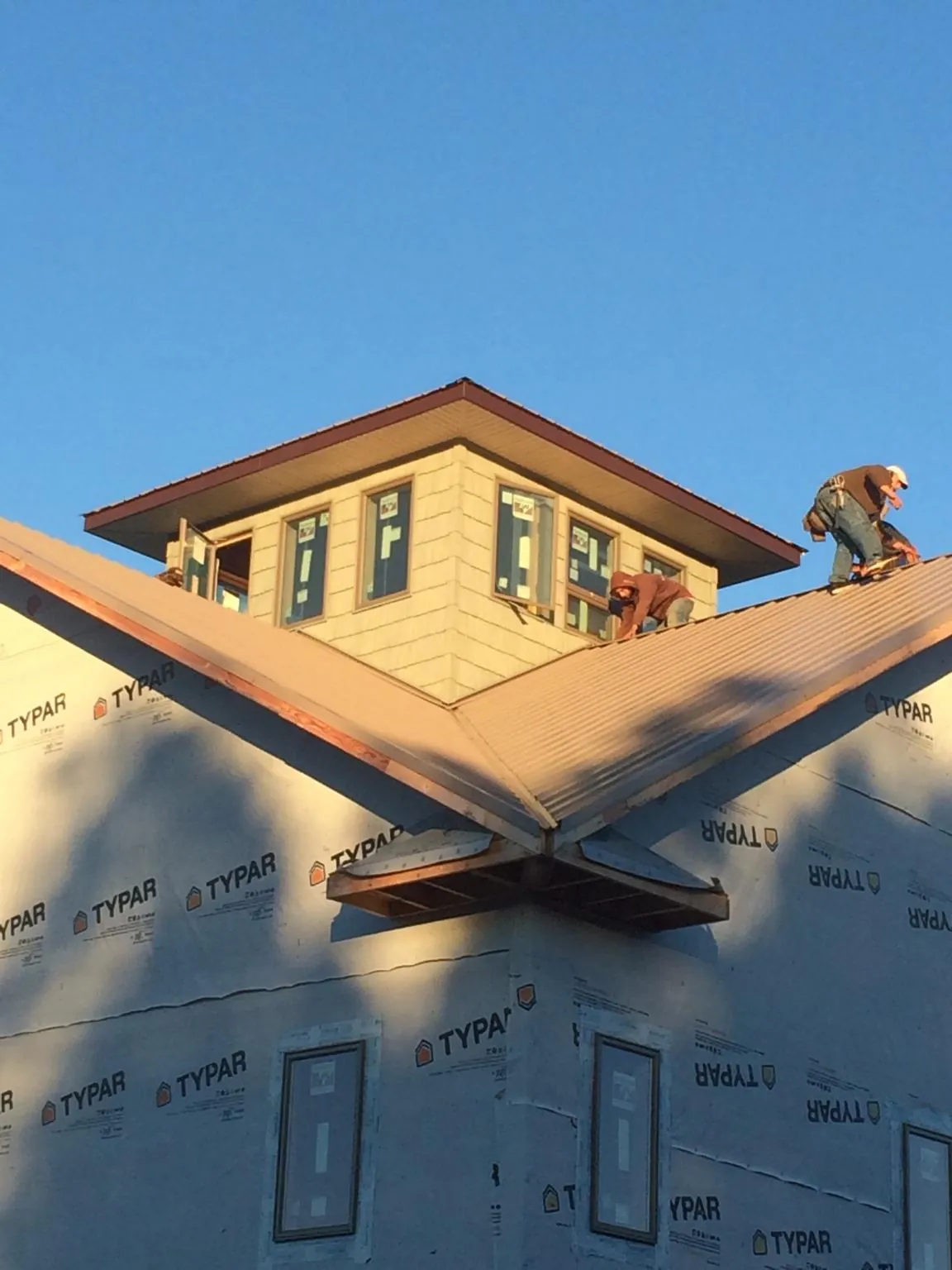 Roofers working around a rooftop cupola on a new metal roof at sunset — Roof Waterproofing in Otter Rock by Roofing Brothers
